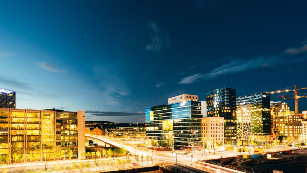 Oslo, Norway. The Night Panoramic View Of Contemporary District Of Black And White High-Rised Buildings In The Center Of City In Bright Illumination In Summer Evening, Blue Sky Background, Copyspace.