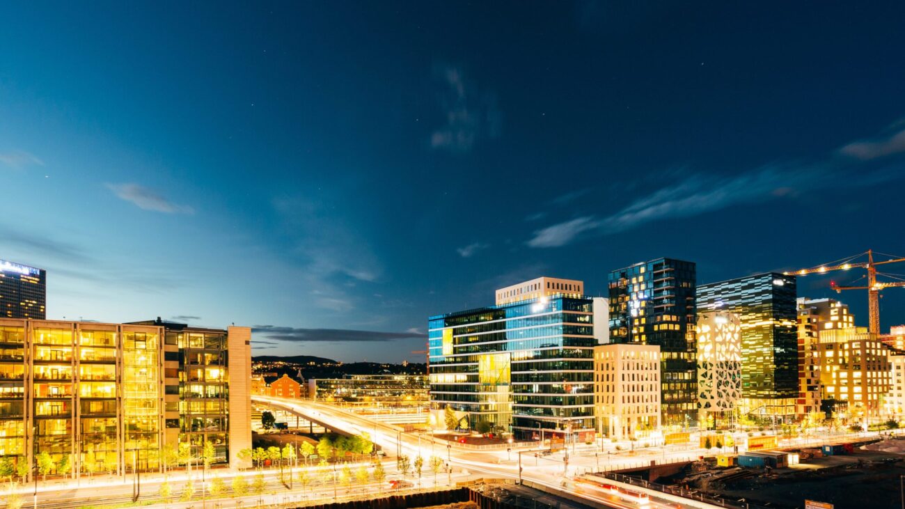 Oslo, Norway. The Night Panoramic View Of Contemporary District Of Black And White High-Rised Buildings In The Center Of City In Bright Illumination In Summer Evening, Blue Sky Background, Copyspace.